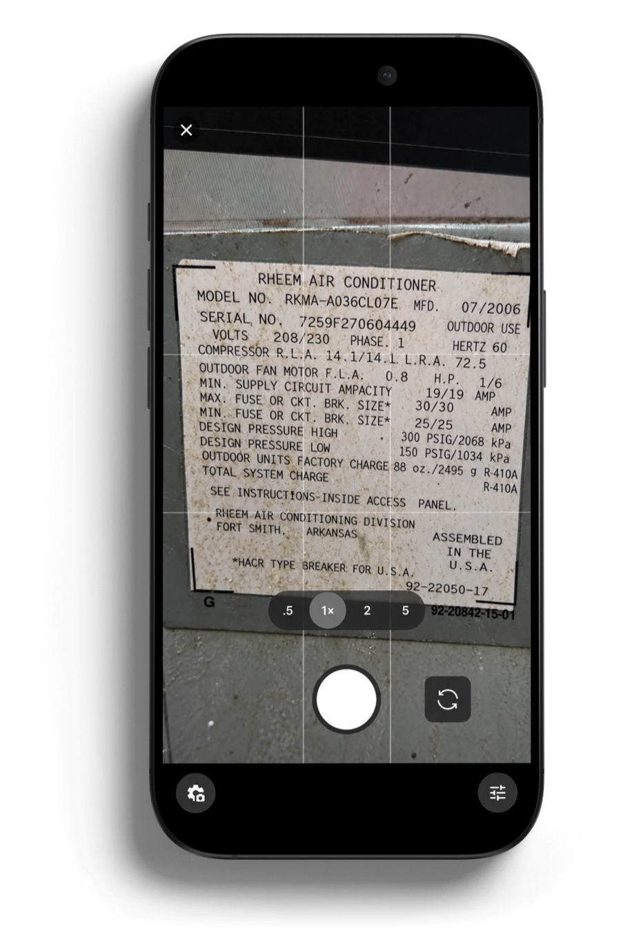 The Bluon nameplate scanner open in the Housecall Pro app, framing the weathered data plate of a Rheem air conditioner.
